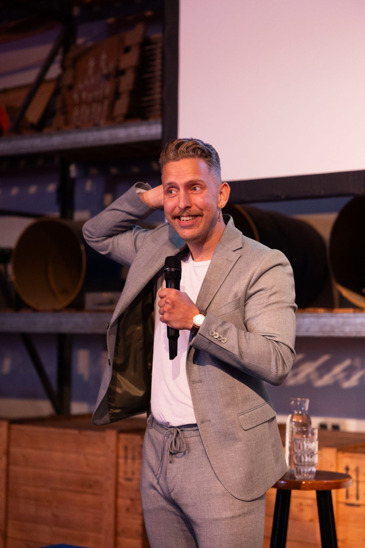 Spreker met microfoon lachend op het podium