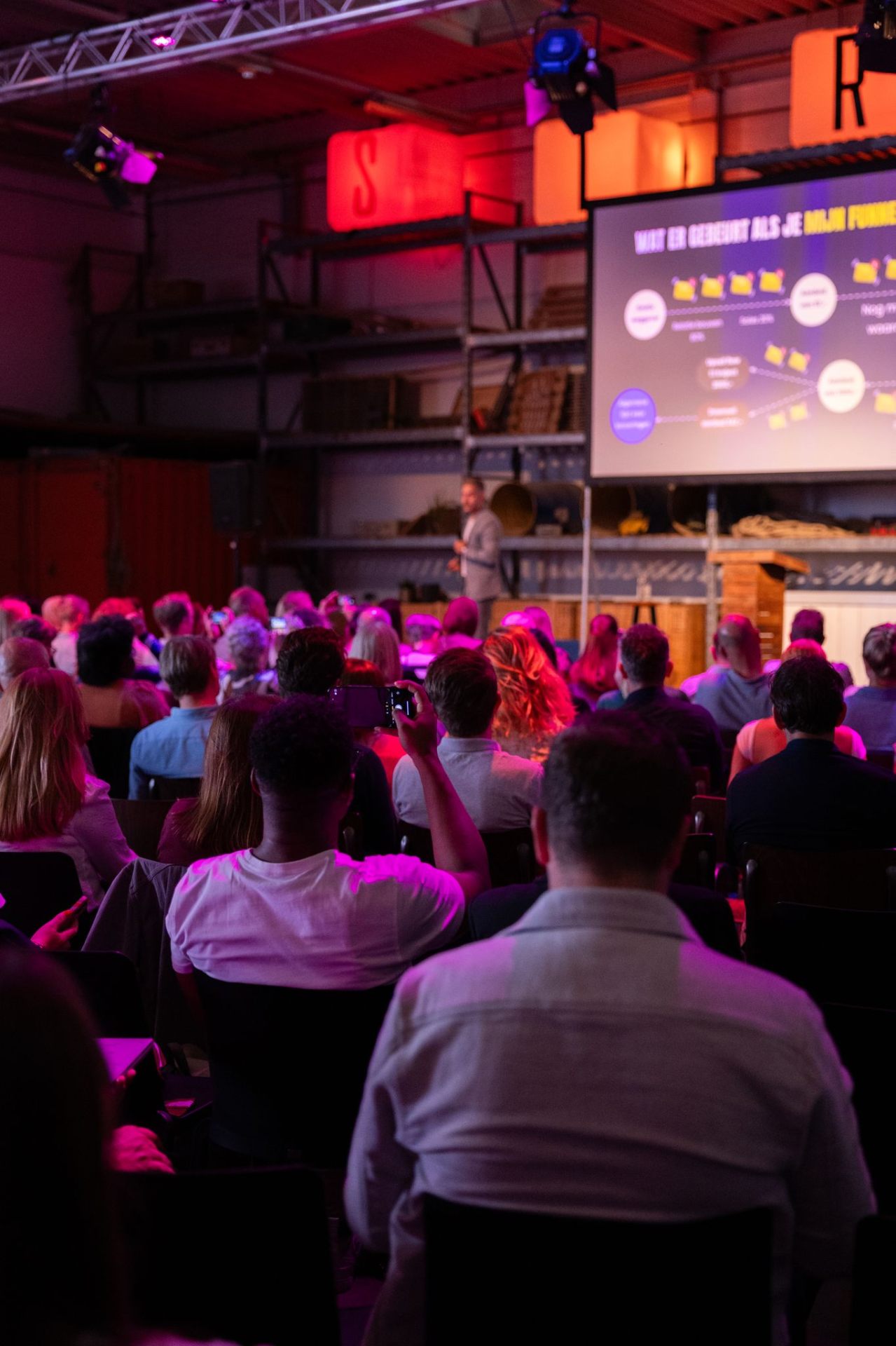 Publiek kijkt naar spreker met funnel-slide